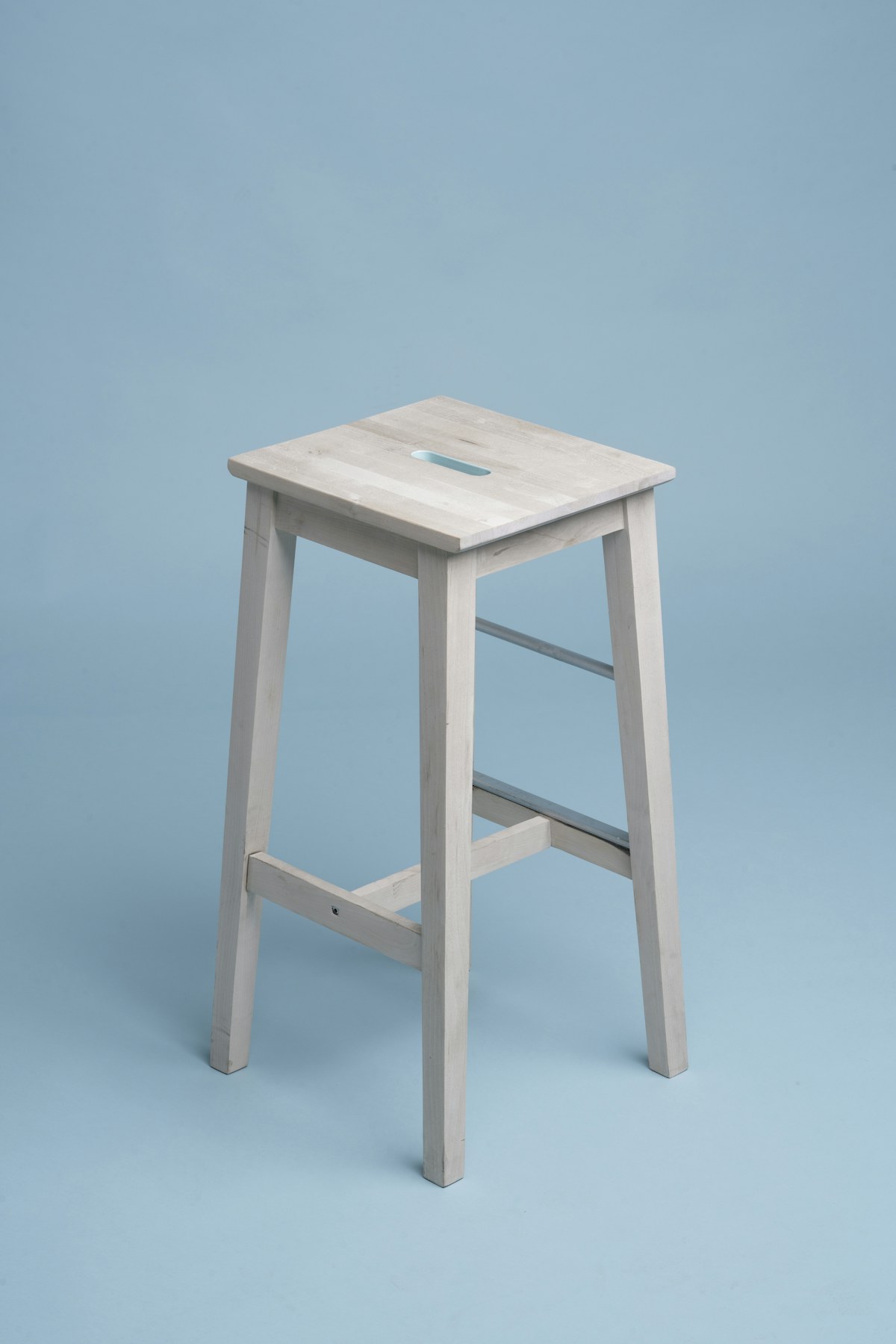 White stool photographed on a blue studio background